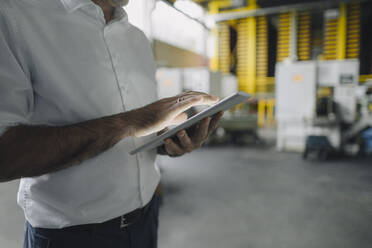 Nahaufnahme eines Geschäftsmannes, der ein Tablet in einer Fabrik benutzt - KNSF07858