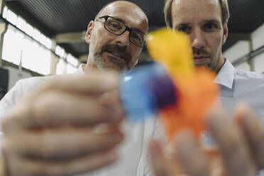 Two men examining workpiece in a factory - KNSF07860