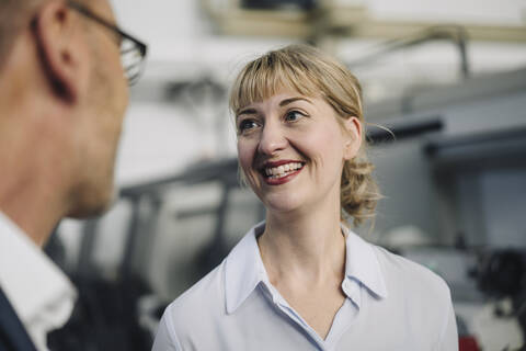 Happy woman looking at businessman in a factory stock photo