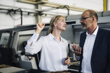 Businessman and woman talking in a factory - KNSF07892