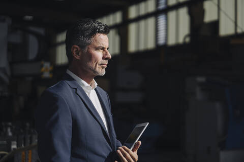 Porträt eines Geschäftsmannes mit Tablet in einer Fabrik, lizenzfreies Stockfoto