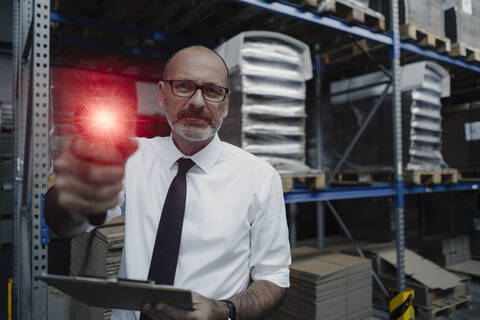 Porträt eines Mannes mit leuchtendem Scanner in einem Fabriklager, lizenzfreies Stockfoto