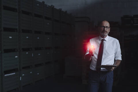 Portrait of man with glowing scanner in factory warehouse stock photo