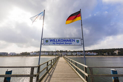 Deutschland, Mecklenburg-Vorpommern, Heringsdorf, Willkommensschild zwischen Nationalflaggen über Holzsteg hängend - WDF05860