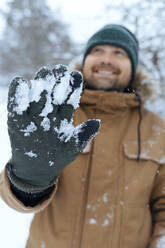 Mann zeigt grünen Handschuh mit Schnee, Nahaufnahme - KNTF04431