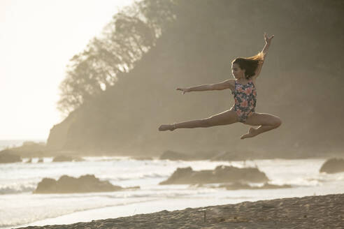 Teenager-Mädchen übt Gymnastik am Meer bei Sonnenuntergang, Jaco Beach, Costa Rica - AMUF00013