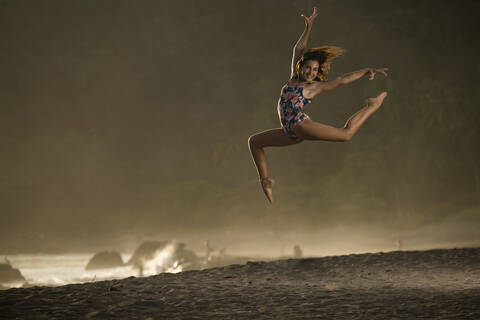 Portrait of happy teenage girl practicing gymnastic on the beach at twilight, Jaco Beach, Costa Rica stock photo