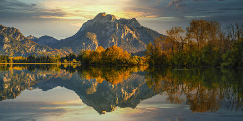 Deutschland, Bayern, Hohenschwangau, Forggensee im Spiegel der umliegenden Bäume und Hügel in der Herbstdämmerung - WGF01316