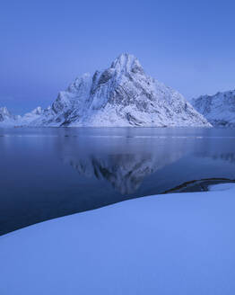 Der Gipfel des Olstind erhebt sich über die Winterlandschaft des Reinefjords, Reine, Lofoten, Norwegen - CAVF76094