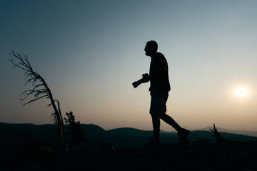 Silhouette eines Mannes mit Kamera bei Sonnenuntergang - CAVF76112
