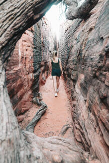 Junge Frau beim Wandern durch einen engen Canyon in Utah - CAVF76191