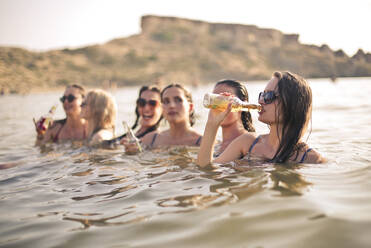 Gruppe von Mädchen am Strand trinkt Bier - CAVF76217