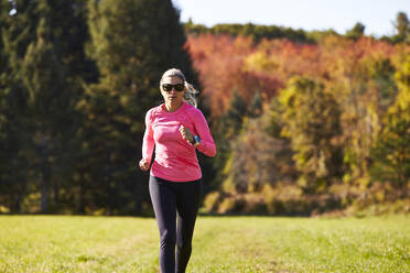 Eine Nahaufnahme einer Frau beim Trailrunning an einem Herbsttag. - CAVF76226