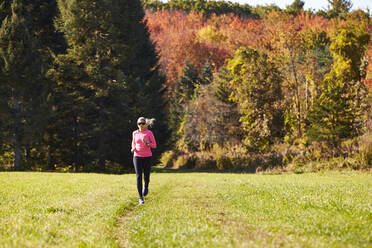 A woman running on a trail on a nice autumn day. - CAVF76228