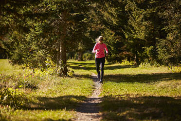 A woman trail running through the trees. - CAVF76230