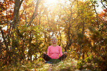 Eine Frau meditiert an einem schönen Herbsttag im Freien. - CAVF76233