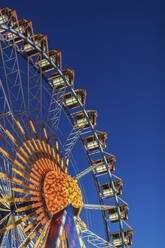 Germany, Bavaria, Munich, Low angle view of Ferris wheel glowing against clear sky at dusk - MMAF01293