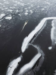 Russia, Saint Petersburg, Sestroretsk, Aerial view of lone boat leaving icy shore of Gulf of Finland - KNTF04461