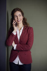 Porträt einer lächelnden Geschäftsfrau am Telefon im Büro - RBF07080