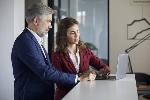 Geschäftsmann und Geschäftsfrau arbeiten zusammen an einem Laptop im Büro - RBF07108