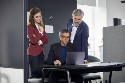 Two businessmen and businesswoman working together on a project in office stock photo