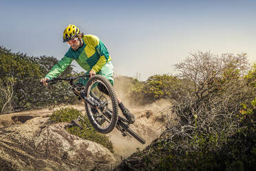 Junger Mann springt mit Mountainbike auf staubigem Singletrail, Fort Ord National Monument Park, Monterey, Kalifornien, USA - MSUF00205