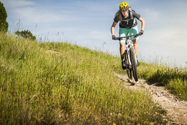 Frau auf Mountainbike fährt vor blauem Himmel einen Weg hinunter, Santa Cruz, Kalifornien, USA - MSUF00229