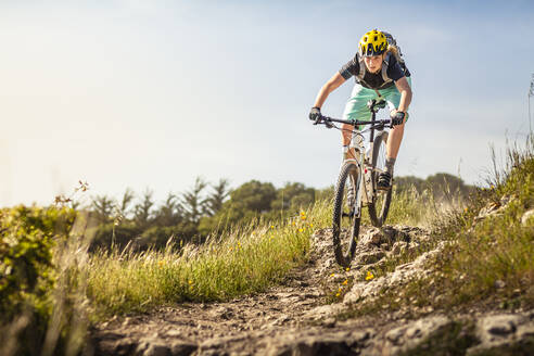 Frau auf Mountainbike fährt vor blauem Himmel einen Weg hinunter, Santa Cruz, Kalifornien, USA - MSUF00231