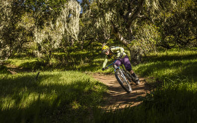 Frau fährt mit dem Mountainbike auf einem Singletrail durch den Wald, Fort Ord National Monument Park, Monterey, Kalifornien, USA - MSUF00241