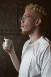 Side view of albino man with glasses, having a coffee in a cafeteria - VEGF01654