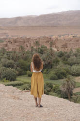 Rückenansicht einer jungen Frau mit Blick auf die Stadt, Ouarzazate, Marokko - AFVF05565