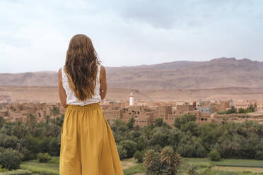 Rückenansicht einer jungen Frau mit Blick auf die Stadt, Ouarzazate, Marokko - AFVF05566