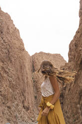 Junge Frau schaut auf Felsen und dreht den Kopf, Ouarzazate, Marokko - AFVF05571