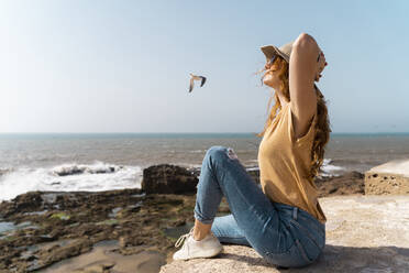 Young woman enjoying sunlight near the sea, Essaouira, Morocco - AFVF05592