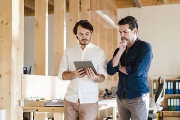 Zwei Geschäftsleute mit Tablet im Gespräch in einem hölzernen Großraumbüro - DIGF09423