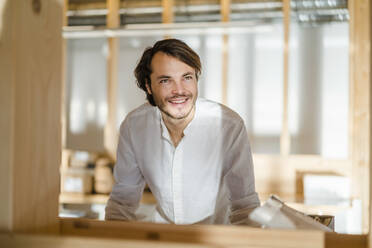 Porträt eines lächelnden Geschäftsmannes in einem Großraumbüro aus Holz - DIGF09428