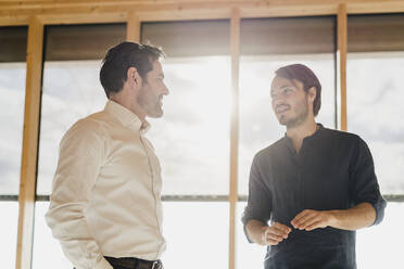 Two businessmen talking at the window in office - DIGF09480