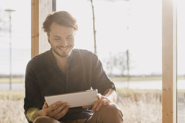 Smiling businessman using tablet in office - DIGF09487