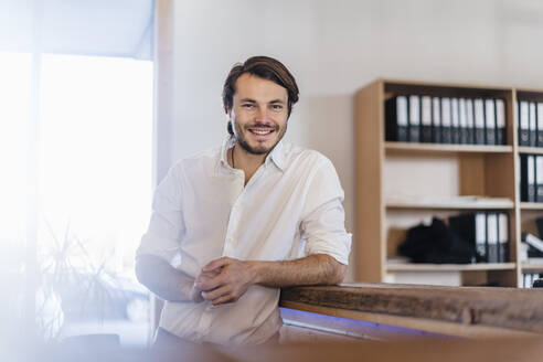 Porträt eines lächelnden Geschäftsmannes in einem Großraumbüro aus Holz - DIGF09504
