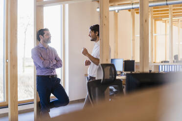 Two businessmen talking in wooden open-plan office - DIGF09509