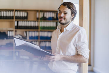 Bbusinessman with folder in wooden open-plan office - DIGF09512