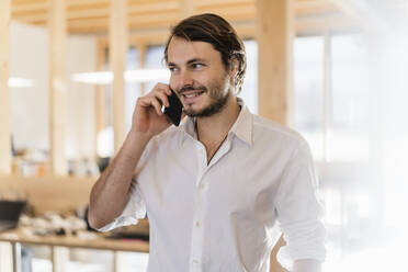 Businessman on the phone in wooden open-plan office - DIGF09526