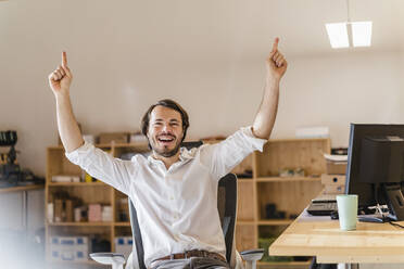 Businessman cheering at desk in office - DIGF09532