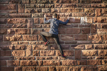 Frau klettert auf Sandsteinmauer - MSUF00242