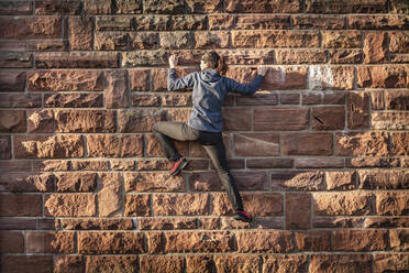 Woman climbing on sandstone brick wall - MSUF00242