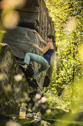 Female climber bouldering on rock, Avegno, Ticino, Switzerland - MSUF00244