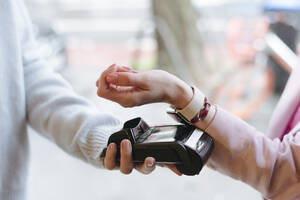 Hand einer Frau, die am POS-Terminal bargeldlos mit ihrer Smartwatch bezahlt - VYF00061
