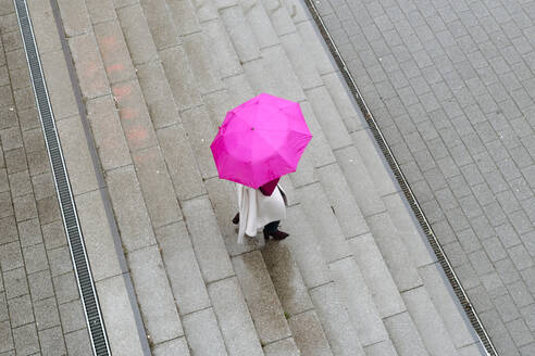 Frau mit rosa Regenschirm auf der Treppe - VYF00063
