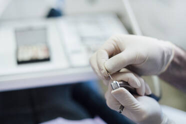 Nahaufnahme eines Zahnarztes bei der Arbeit an einem zahnärztlichen Instrument - JCMF00410