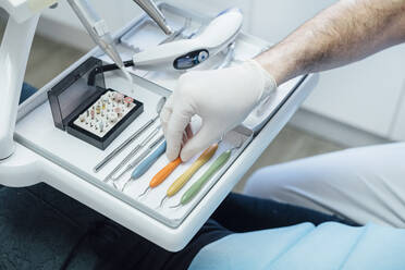 Close-up of dentist taking dental instrument from tray - JCMF00417